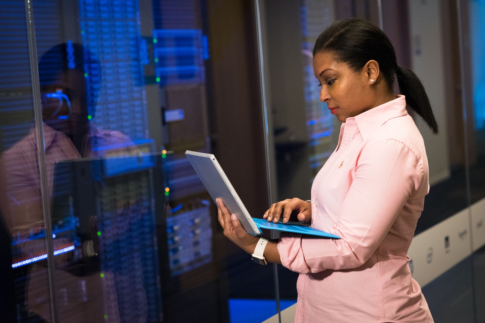 A person typing at a laptop in front of rack-mounted servers