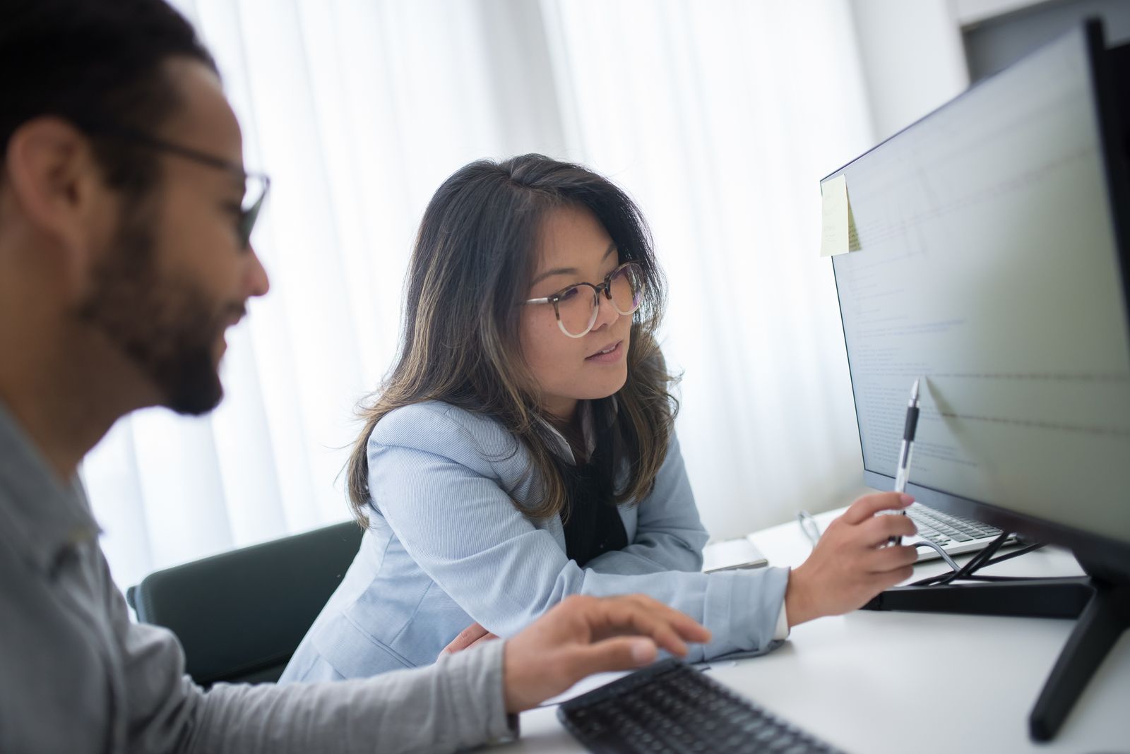 Three colleagues reviewing a monitor together at a desk