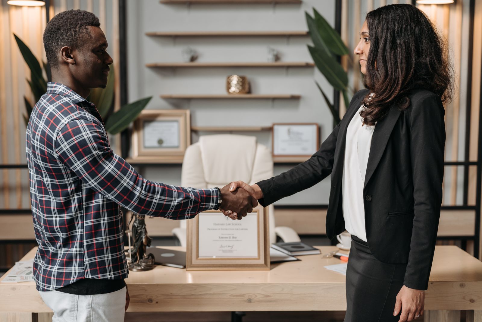Two people shaking hands across a desk